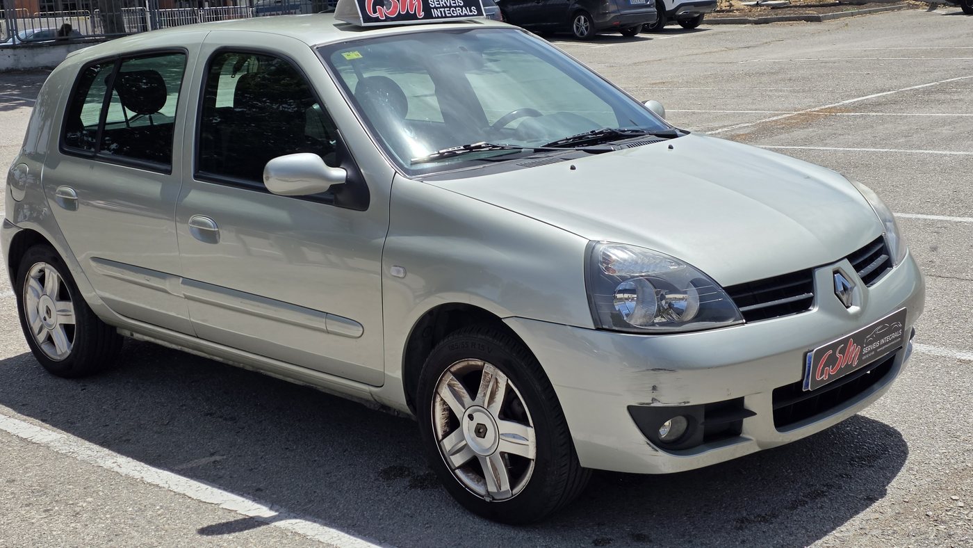 Renault Clio Campus argentée de 2008 de face et de trois quarts en juin 2026, avec une rayure sur le pare-chocs avant et le cache-plaque GSM