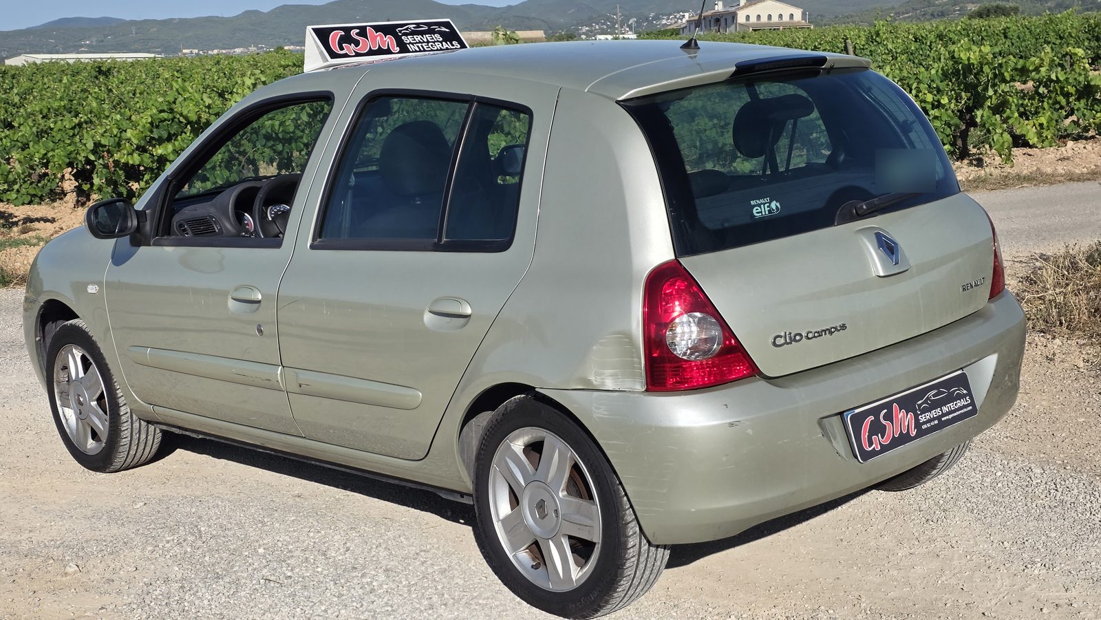 Renault Clio Campus vue de l'arrière côté gauche avant la réparation, avec le choc sur l'angle arrière, et le cache-plaque GSM