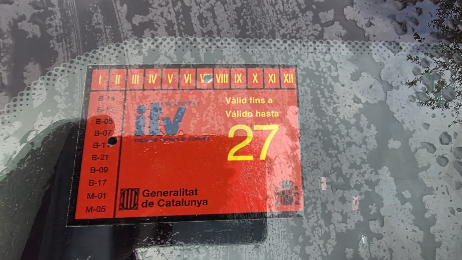Vignette rouge du contrôle technique (ITV) de la Generalitat de Catalunya sur la vitre de la Renault Clio Campus, valable jusqu'en 2027